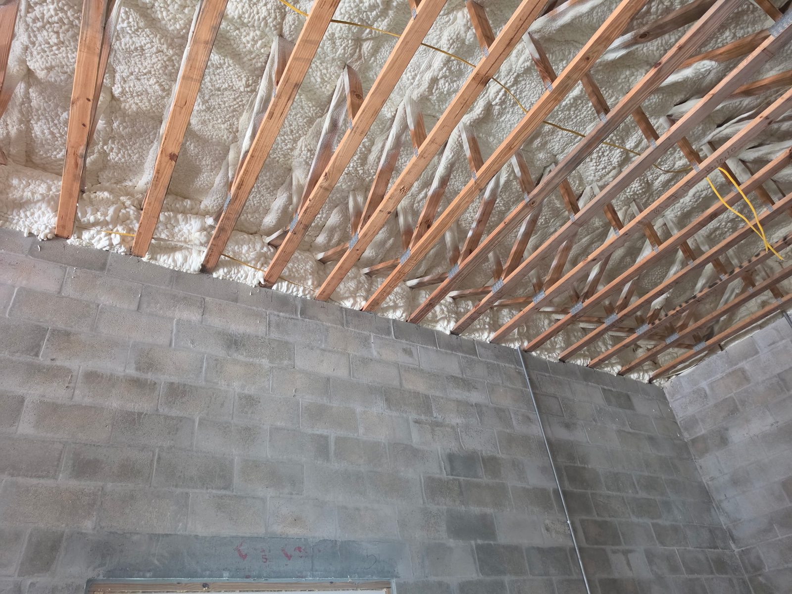 Closed-cell spray foam freshly applied between attic rafters on a Central Florida home
