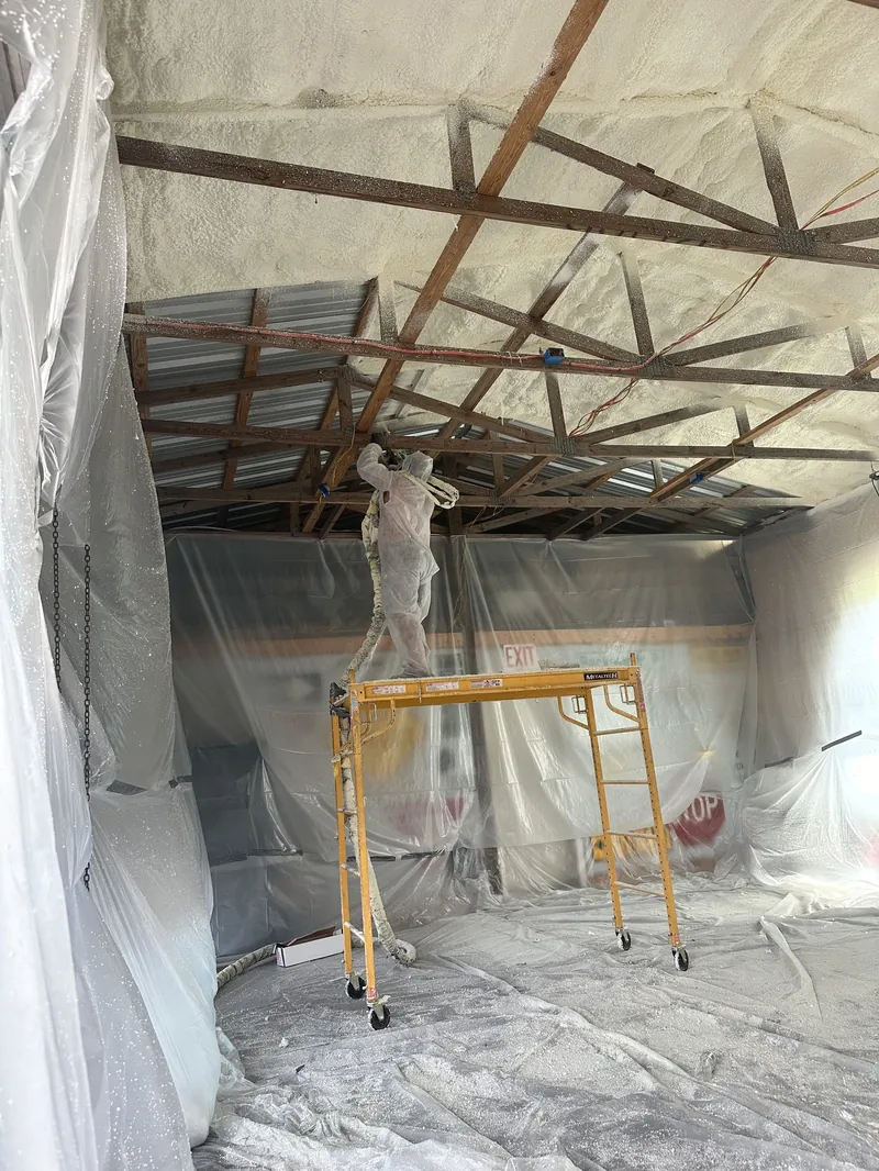 Insulflo installer spraying foam insulation from scaffolding during a commercial job